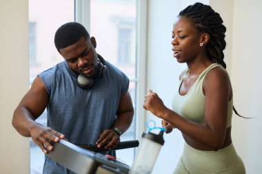 Spor salonunda koşu bandında egzersiz yapan, sohbet eden ve spor yapmaktan zevk alan iki Afrikalı Amerikalı.