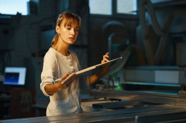 Tahta döşemeyi inceleyen genç bir kadın.