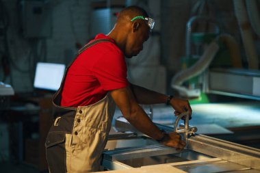 Afrikalı Amerikalı işçi fabrikada odunla torna tezgahında çalışıyor.