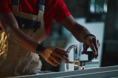 Ahşap atölyesindeki torna işini kontrol eden üniformalı işçilere yakın plan.