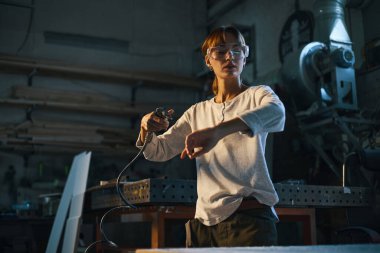 İşten sonra özel ekipmanla giysilerden talaş üfleyen bir işçi.