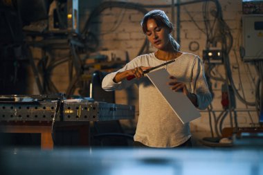 İş yerinin yanındaki atölyede çalışan ve kıyma makinesiyle tahta tutan bir kadın işçi.