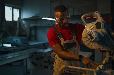 Afrikalı Amerikalı işçi fabrikada çalışmadan önce torna tezgahını kuruyor.