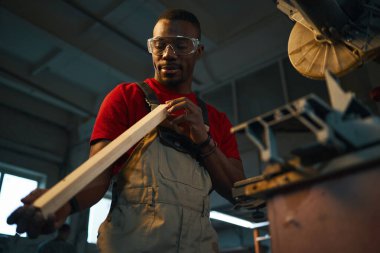 Torna tezgahında kestikten sonra ahşap detayı inceleyen işçinin düşük açılı görüntüsü