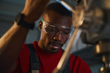 Torna tezgahında çalışan koruyucu gözlüklü Afrikalı Amerikalı manuel işçi.