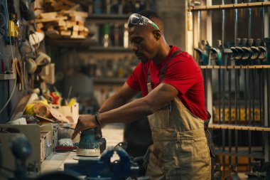 Afrikalı Amerikalı adam atölyede cilalama makinesiyle çalışıyor.