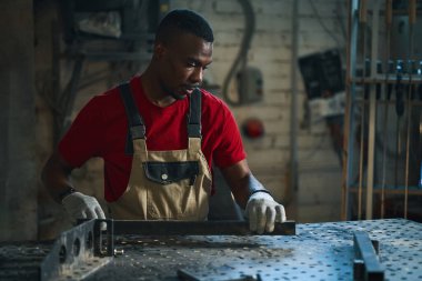 Afrikalı Amerikalı işçi atölyede metal çerçeve yapıyor.