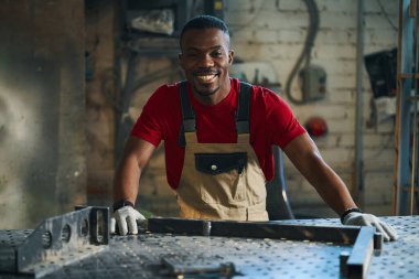 Afro-Amerikan işçilerin portresi kameraya gülümserken levha yapımı için metal çerçeve yapıyor.