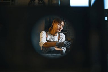 Atölyede metal işleriyle uğraşan genç bir kadın.