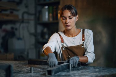 Atölyede metal ve imalat tabelasından çerçeve yapan kadın işçi