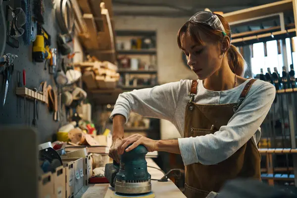 Atölyesinde cilalama makinesi kullanan bir kadın.