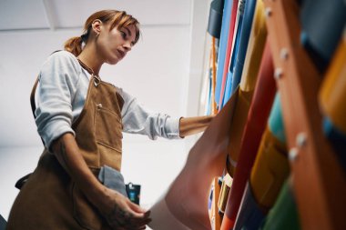 Atölyede renkli kağıtlarla çalışan bir kadının düşük açılı görüntüsü