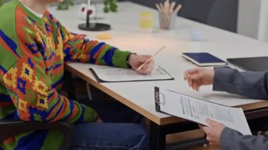 Masadaki iş görüşmesi sırasında genç bir çalışanın elini sıkan kadın istihdam müdürünün yan görünüşü