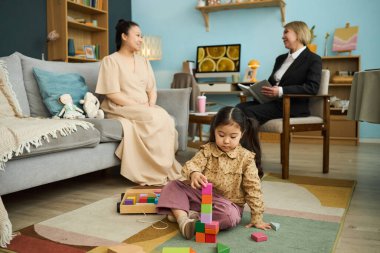 Bakıcı, rahat bir yaşam alanındaki çocuk istifleme bloklarıyla meşgul. Kadın ve çocuk eğitici ve eğlenceli bir ortam yaratıyor.