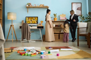 Çok ırklı aile, arka planda raflar ve sanat eserleriyle kapalı bir etkinliğe katılıyor.