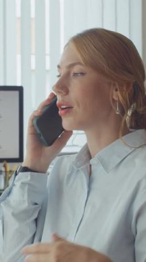 Modern ofiste çalışırken akıllı telefondan genç bayan çalışanın dikey görüntüsü.