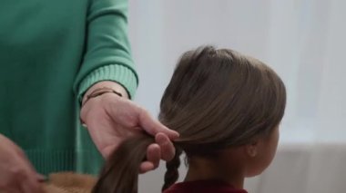 Tanımlanamayan bir annenin uzun siyah saçlarını içeride taramasının görüntüsü.