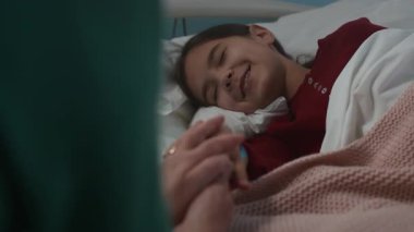 Hastanenin koğuşunda yatan hasta kızını destekleyen tanınmayan bir annenin el kamerası görüntüsü.