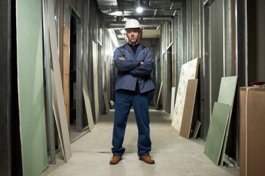 İnşaat alanında çalışırken portre için poz veren birleşik giyimli profesyonel bir müteahhit.