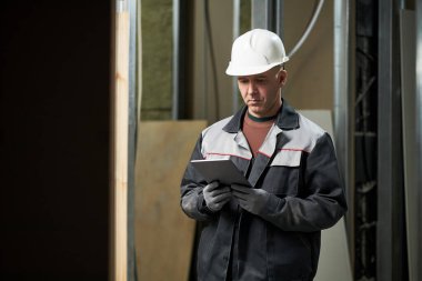 İnşaat alanında çalışırken tablet ekranına bakan olgun inşaatçı