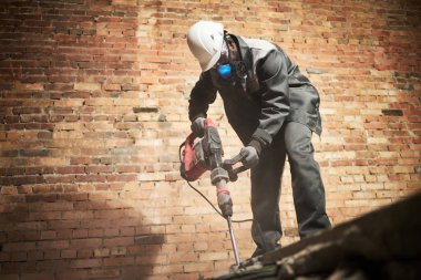 Afrika kökenli Amerikalı 'nın tuğla duvarlı eski beton zemini yıkarken düşük açılı görüntüsü.