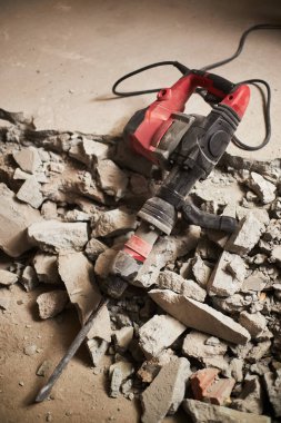 Çimento parçalarının üzerinde bina tozu ile kaplı büyük kaya matkabının dikey çekimi.