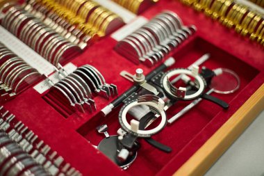 Kırmızı bir çantaya yerleştirilmiş çeşitli göz hekimliği test lensleri koleksiyonu. Seçimlerde farklı boyut ve şekiller, görme ve göz sağlığı muayeneleri için gereklidir