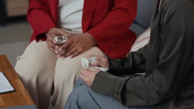 Kadın Afrikalı Amerikalı danışmanın terapi seansında hastaya su verirken yukarı kaldır.