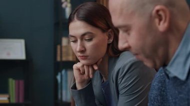 Orta yaşlı beyaz bir adamın danışmanlık seansı sırasında karısının yanında otururken kağıda çizim yaptığı bir fotoğraf.