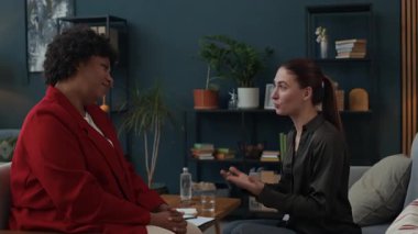 Orta yaşlı Afrikalı Amerikalı danışmanın terapi seansı sırasında genç beyaz kadın hastalara destek vermesi.