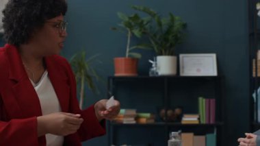 Kafkasyalı çifte terapi sırasında kart sorularıyla danışmanlık yapan Afrikalı Amerikalı kadın.