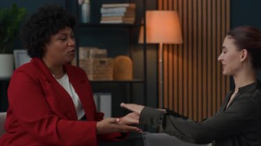 Yetişkin Afrikalı Amerikalı danışmanın terapi seansı sırasında beyaz kadın hastalarla egzersiz yaptığı orta boy bir fotoğraf.