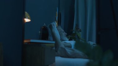 Olgun bir adamın esnemesinin ayna yansıması, sonra da akşam evde rahat bir yatakta uyuyakalıyor.