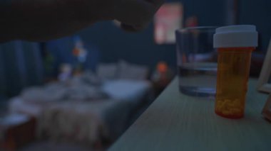 Üst düzey bir adamın uyku hapları alıp camdan su içtiği, sonra da geceleri karanlık bir odada yattığı bir fotoğraf.