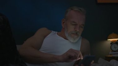 Son sınıf öğrencisi gecenin bir yarısı yatakta dinleniyor, akıllı telefonuyla yazı yazıyor ve kaydırıyor.