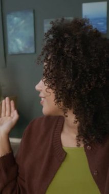 Siyahi kadınların iş hakkında konuştuğu ve ofiste video çekerken iş arkadaşını kameraya tanıttığı dikey çekim.