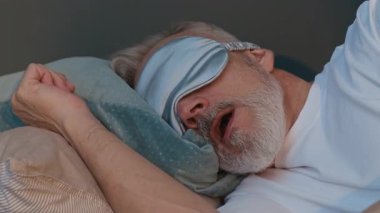 Son sınıf öğrencisinin yatakta uyanıp, saten uyku maskesini çıkarırken ve sabah evde tekrar uykuya dalarken yakın plan çekimi.