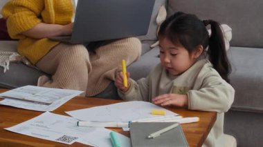 Annesi evdeki bilgisayardan faturaları öderken küçük Asyalı kızın kağıt üzerine resim çekimini kaldır.