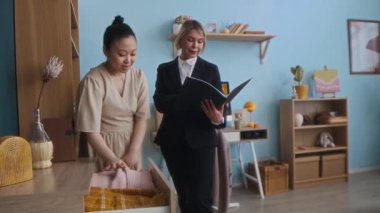 Orta yaşlı Kafkas sosyal hizmet görevlisinin randevusu sırasında bekar Asyalı hamile kadının yaşam koşullarını kontrol ederken not aldığı orta ölçekli bir fotoğraf.