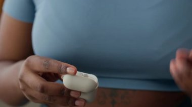 Aktif giyimli iri yarı siyahi kadının yavaş çekimde kablosuz kulaklıkları dikkatle yerleştirirken, antrenmana hazırlanırken, odaklandığını ve kararlılığını gösterirken.