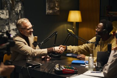 Adam yazarla el sıkışıyor ve podcast sırasında stüdyoda onu selamlıyor.