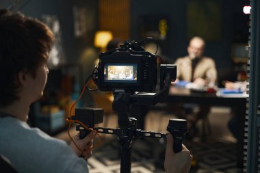 Operatör, stüdyoda podcast videosu çekmek için profesyonel kamera kullanıyor.