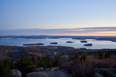 A sweeping view over Bar Harbor Maine from Cadillac Mountain in Acadia National Park. It is just before sunrise, and the sleepy little town begins to awake. The sky is mostly blue with some pink and orange. It is the off-season, and autumn is almost  clipart