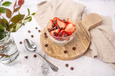 Vanilyalı yoğurt kasesi üzerine taze çilek ve şekersiz çikolata parçacıkları..