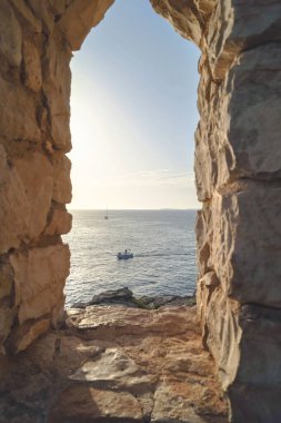 Adriyatik 'teki antik bir binanın penceresinden kayalık bir sahilde manzara.
