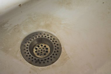 Kirli, tıkanmış lavabo lekelerle ve boşanmalarla dolu. Lekeli ve sızdıran kirli su musluğu