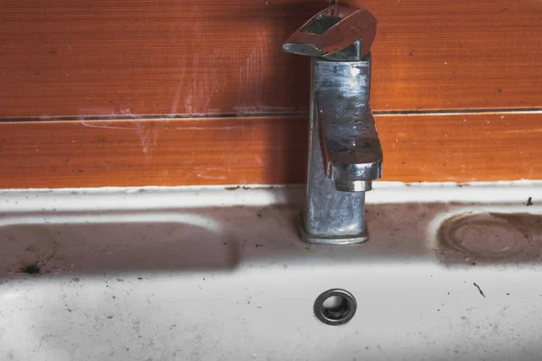 Kirli, tıkanmış lavabo lekelerle ve boşanmalarla dolu. Lekeli ve sızdıran kirli su musluğu