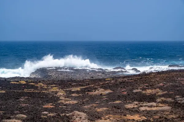 Tenesera 'nın engebeli kıyı şeridinde dalgalar kopuyor, Lanzarote, güzel bir yaz gününde.