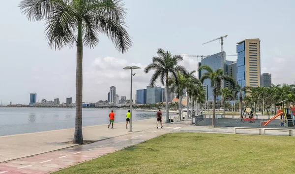 stock image Luanda Angola - 09 17 2022: View at the Luanda bay and Luanda marginal, pedestrian pathway with tropical palm trees, downtown lifestyle, Cabo Island, Port of Luanda and modern skyscrapers