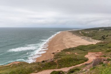 Nazare 'nin kuzey sahilindeki muhteşem manzara, en yüksek dalgaların dalgalandığı ünlü ikonik plaj, Atlantik okyanusu ve gökyüzü, Nazare Portekiz...